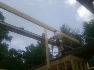 Carpenter setting a ridge beam over a new addition frame — Ice Dam Removal by Roofing Brothers in Butler