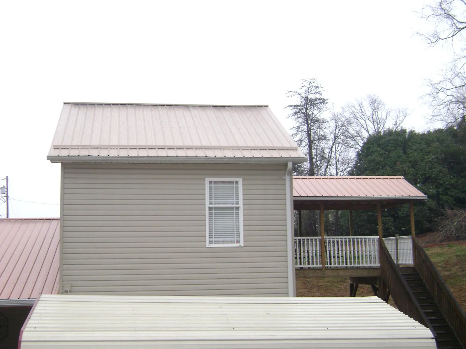Tan metal roofs on a two story addition and attached porch, from a Roof Replacement job in Butler